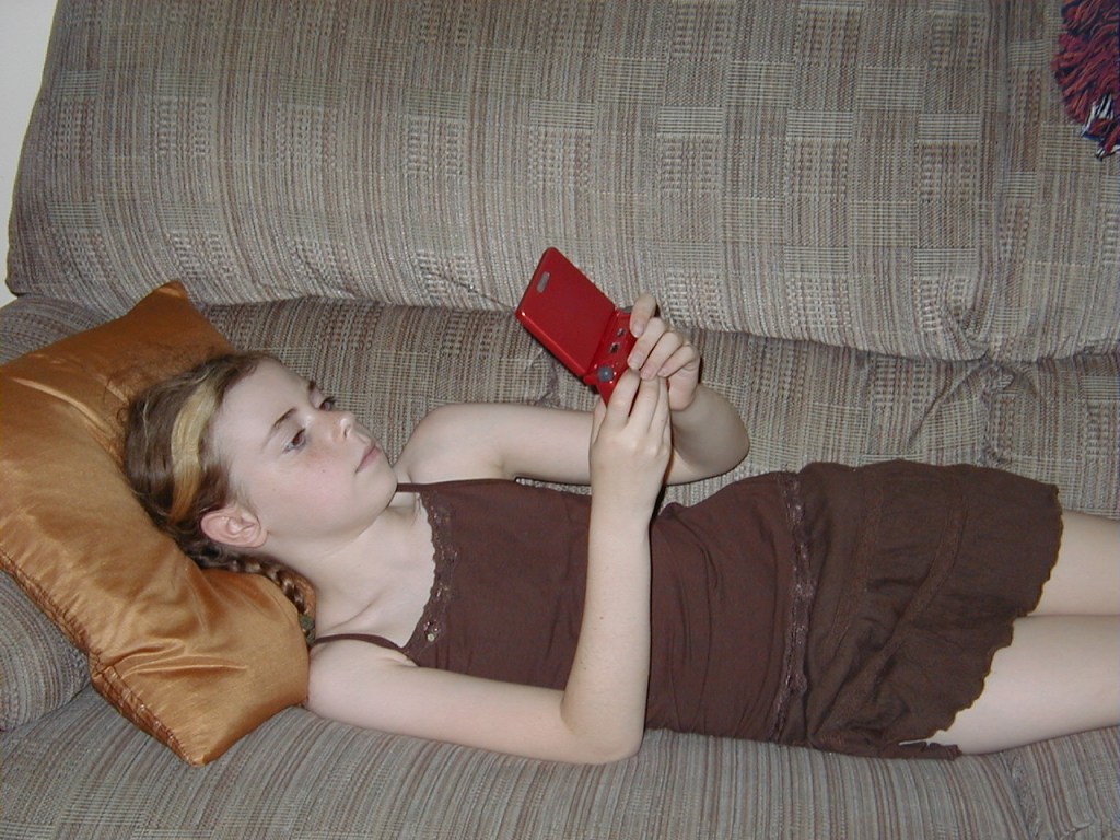 Image of Young girl plays on a red Game Boy Advance SP, 2006, gift of Kristy Allen Hisert. The Strong National Museum of Play, Rochester, New York.