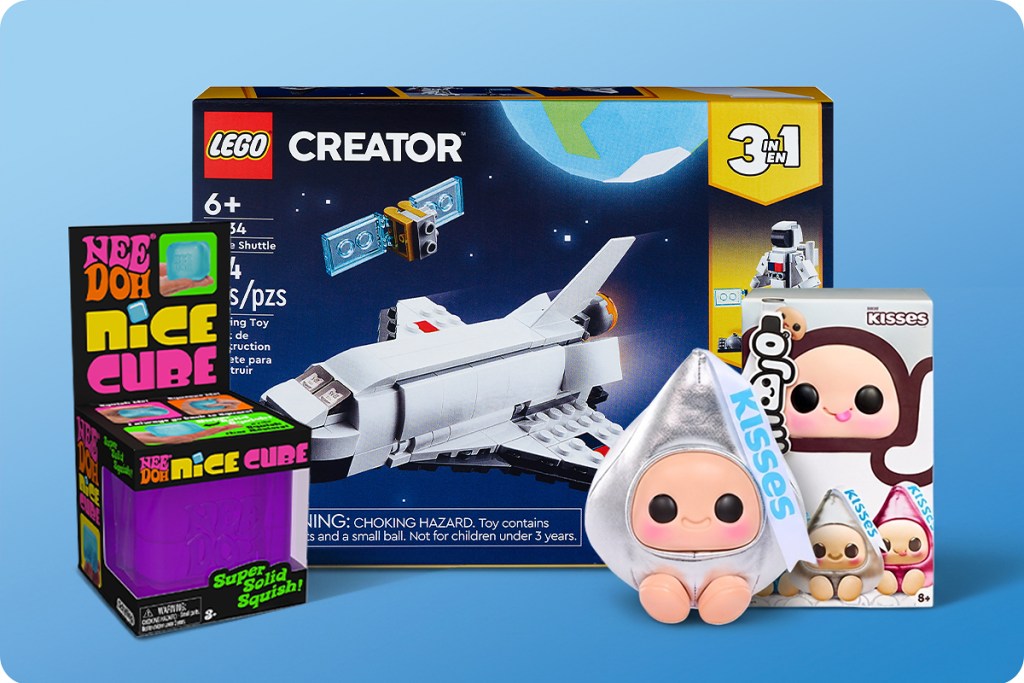 A colorful assortment of toys including a LEGO Creator space shuttle set, a Nee Doh Nice Cube, and a Kisses plush toy, all displayed on a light blue background.