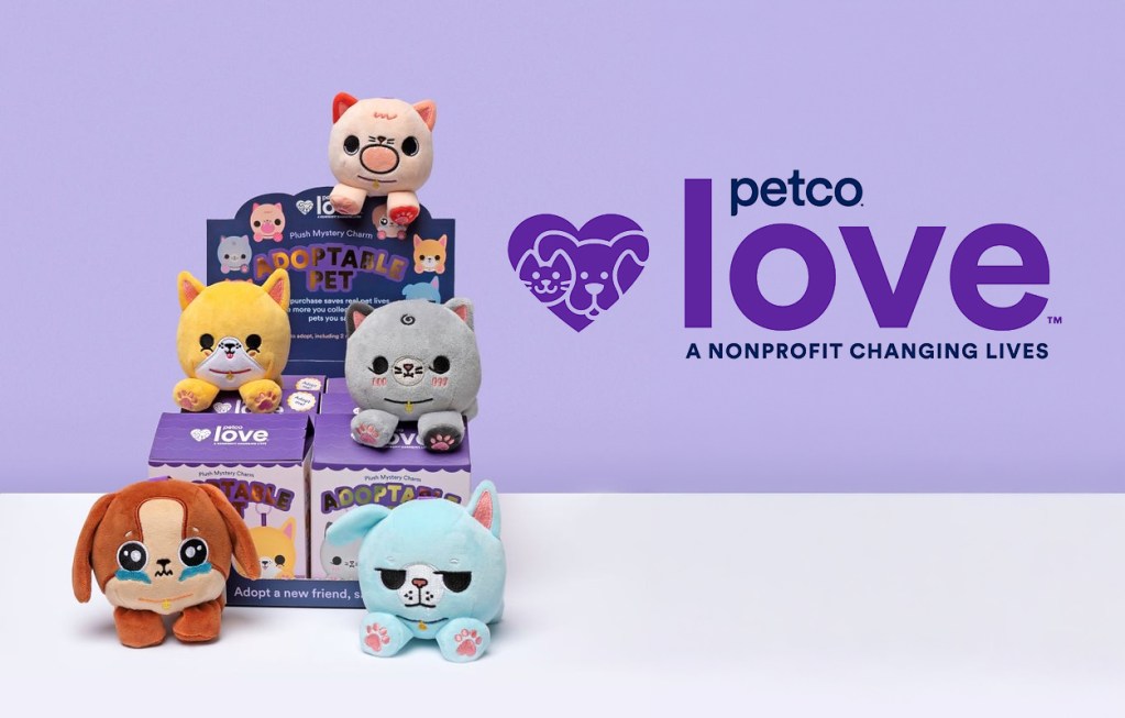 A display of colorful plush pets including a cat, dog, and other animals, alongside a sign promoting Petco Love, a nonprofit focused on animal welfare. The background is a light purple, emphasizing the theme of adopting pets.